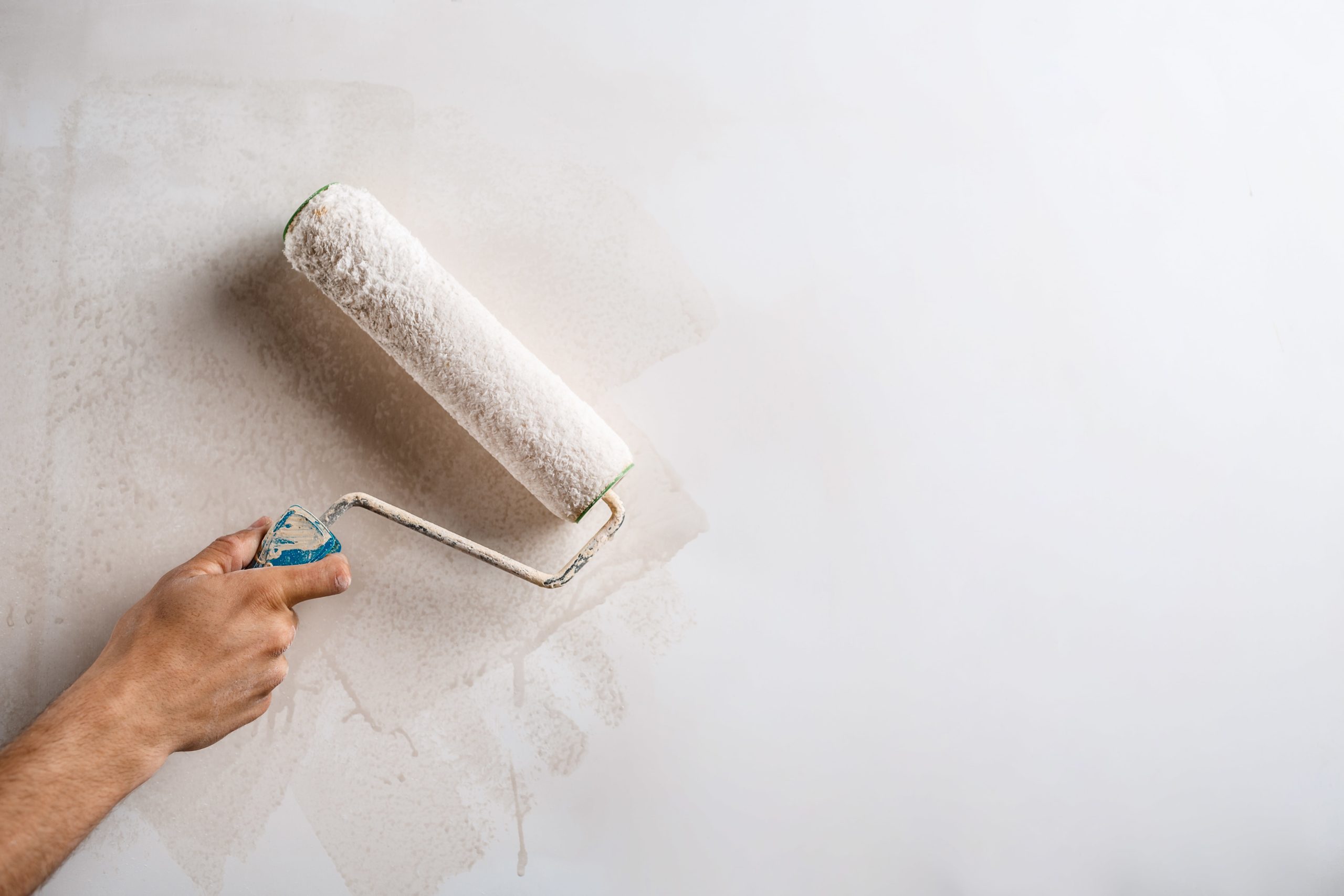 close-up-hand-painting-wall-with-roller-min